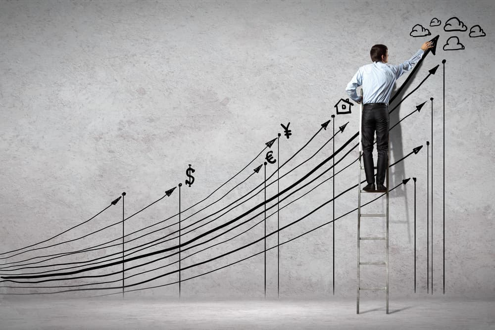 A man drawing additional images to complement a line graph drawn on the wall