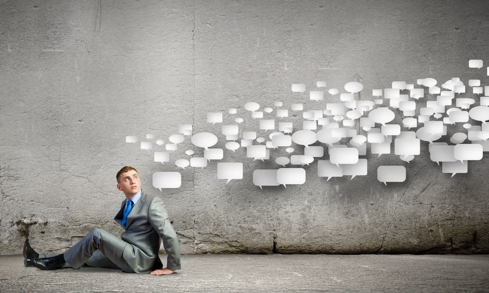 A man in a suit with many thought bubbles floating above his head