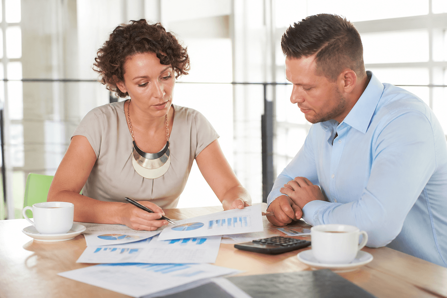 Two people reviewing printed charts at a bright conference table