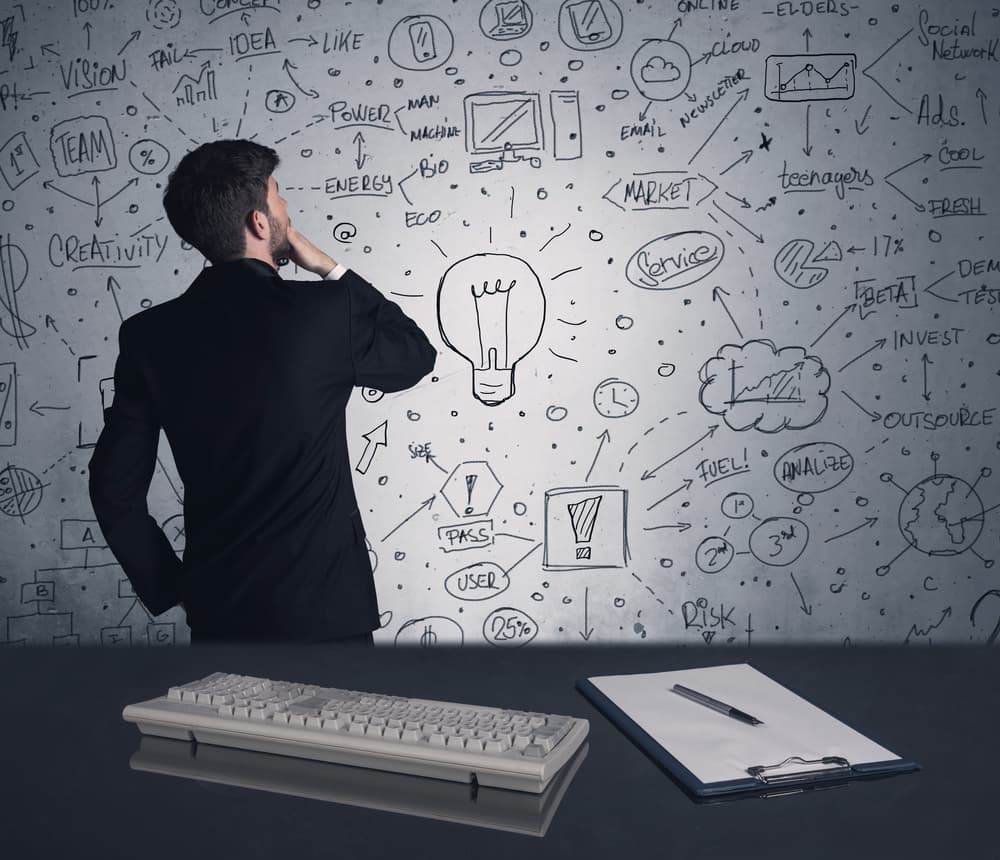 A man holding his chin as he looks at a wall of ideas