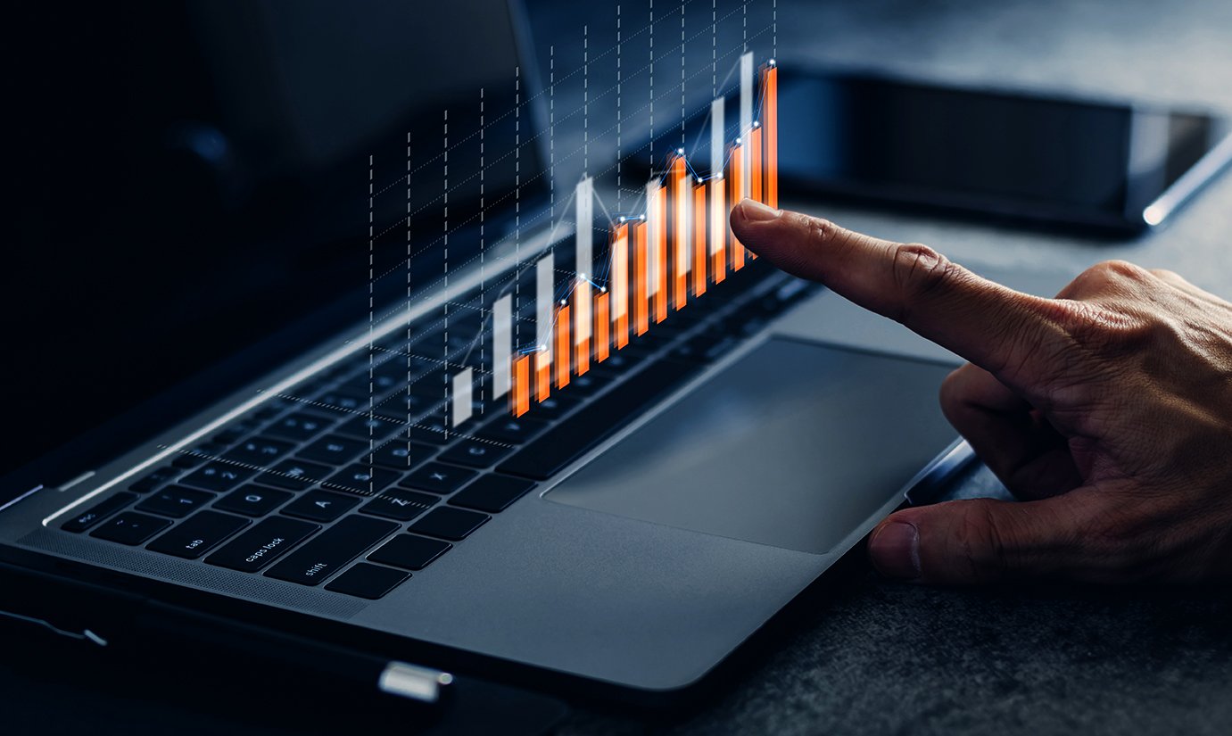 A finger pointing at a chart on a laptop