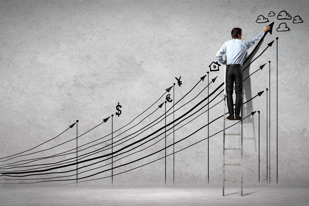 A man drawing additional images to complement a line graph drawn on the wall
