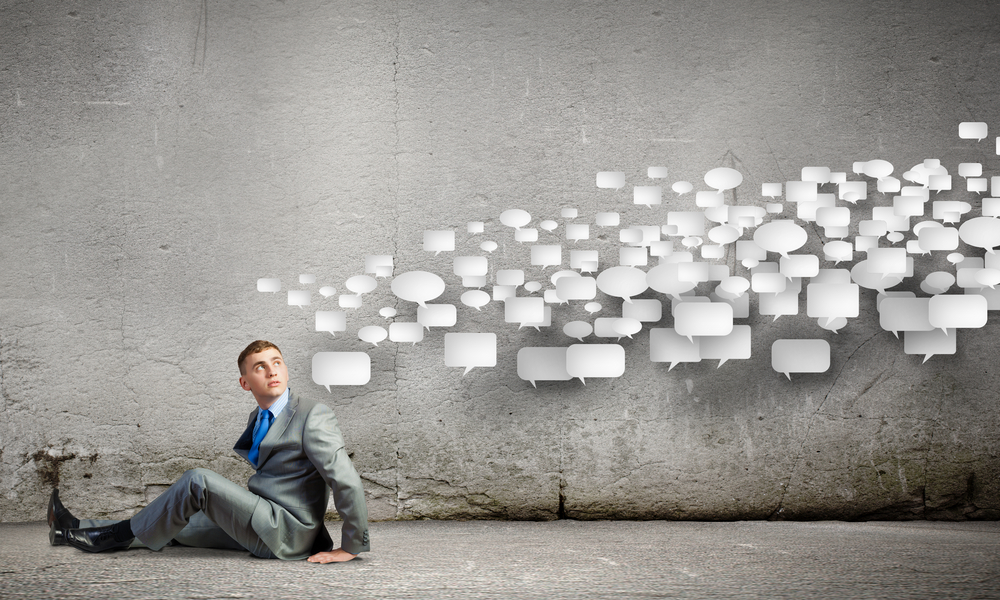 A man in a suit with many thought bubbles floating above his head