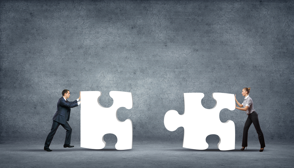 A man and woman pushing giant puzzle pieces together