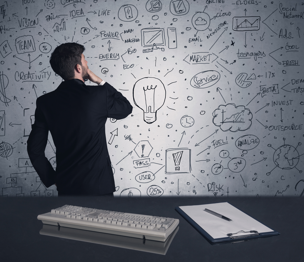 A man holding his chin as he looks at a wall of ideas