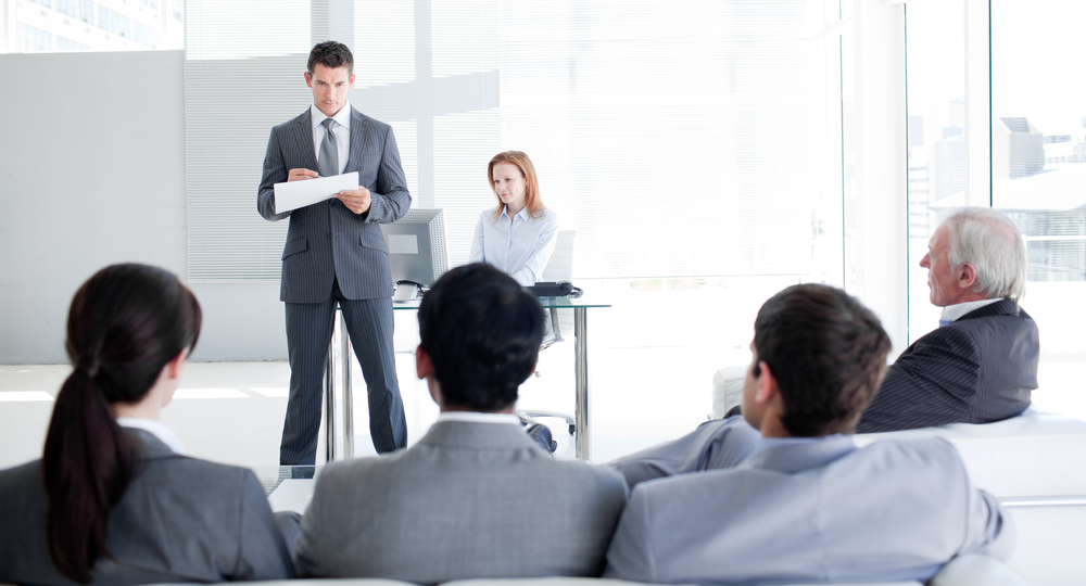A man speaking in front of a group of professionals