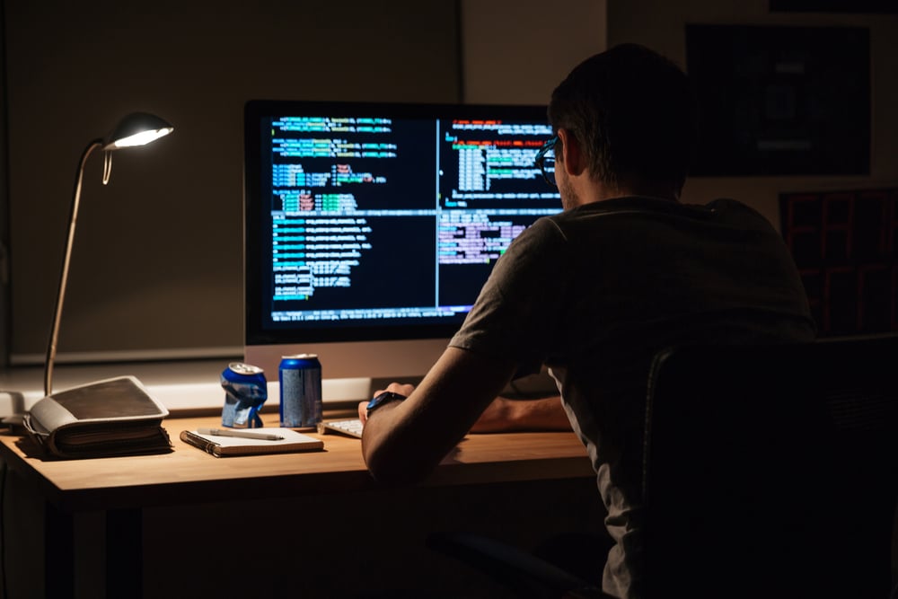 A man at a dark desk, with a few empty soda cans nearby