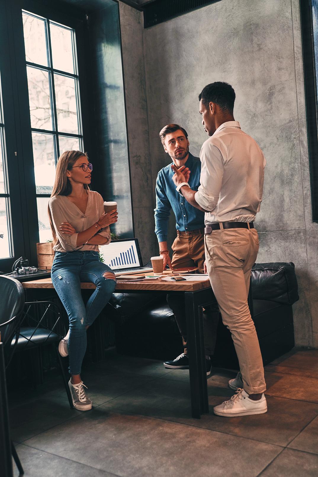 Three coworkers discussing business strategy over coffee