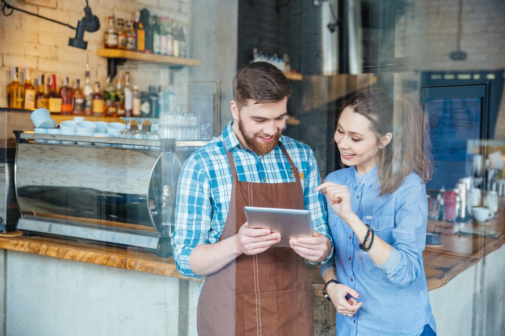 Man and woman smiling as they look at a tablet