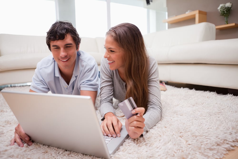 A man and woman smiling in front of a laptop