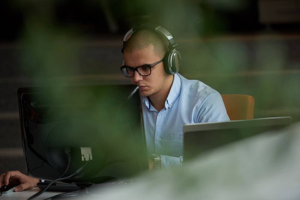 A man wearing headphones, sitting in front of a laptop