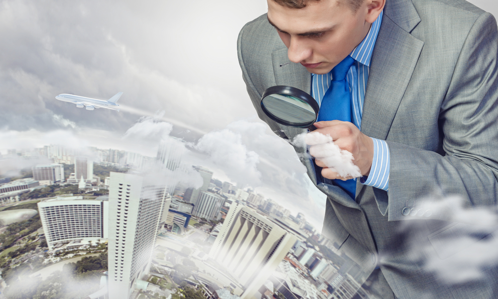 A man with a magnifying glass standing above a city